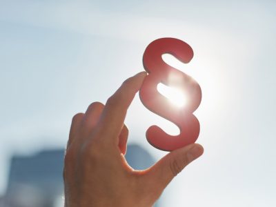 Hand hält Paragraphen in die Sonne als Zeichen für Recht und Gerechtigkeit